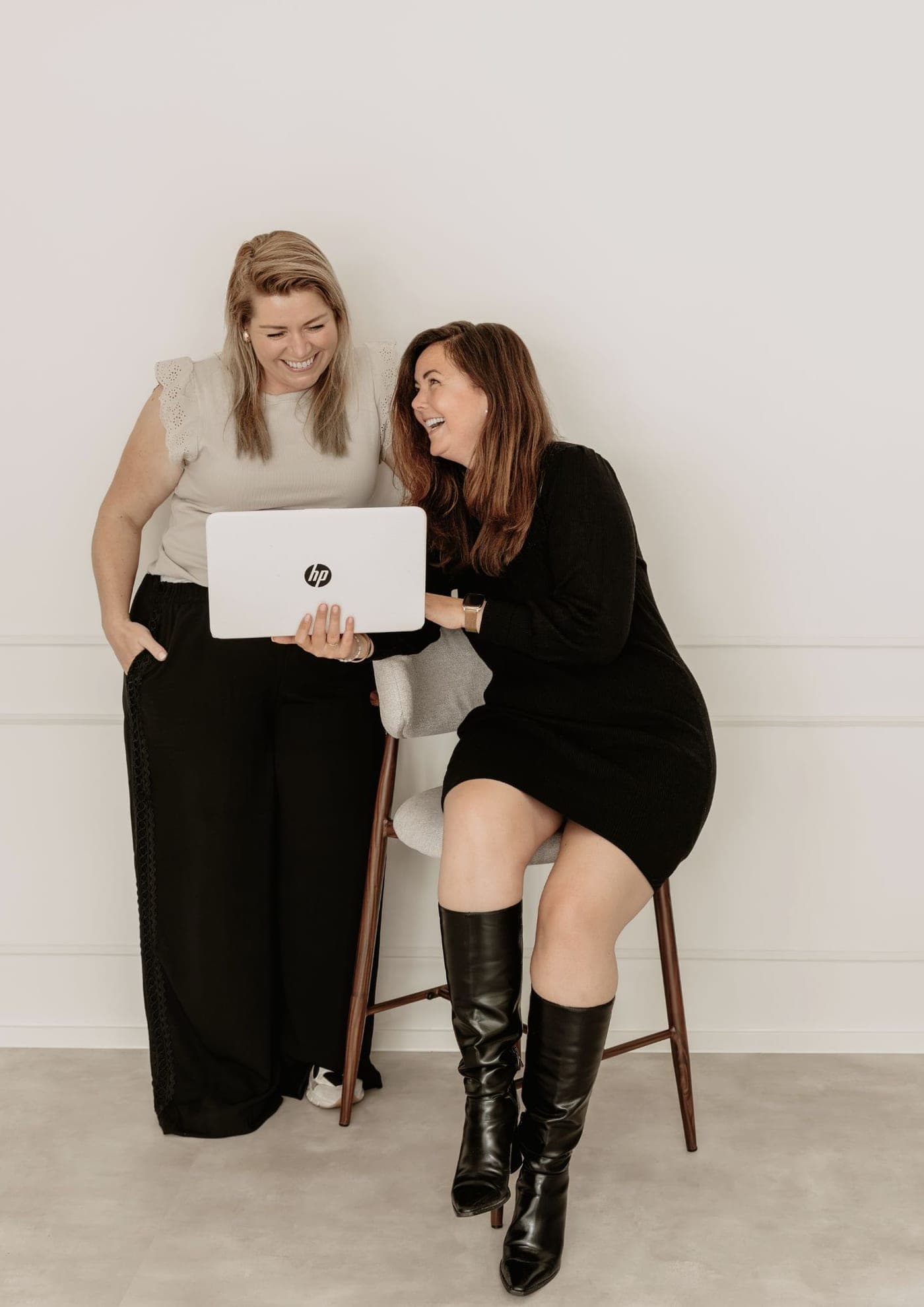 De twee oprichters van de Medisch VA Academie kijken samen lachend naar een laptop